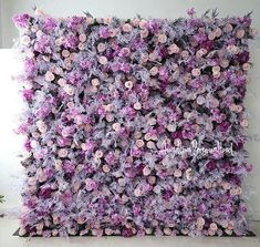 a purple and white flowered wall hanging on the side of a building with flowers all over it