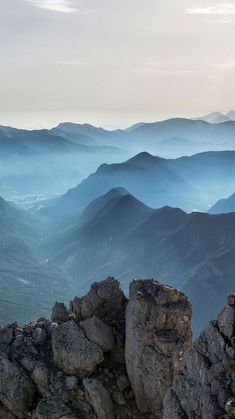 a person sitting on top of a mountain with a cell phone in their hand and mountains in the background