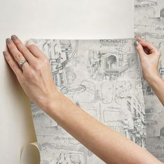 two hands holding onto a piece of paper that has drawings on it and is being drawn