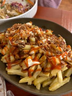 a plate full of french fries covered in toppings next to a bowl of salad