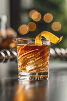 a close up of a glass with an orange peel on the rim and ice in it