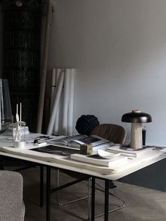 a table with books and other items on it next to a chair in the background