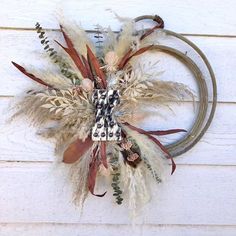 a wreath with feathers hanging on the side of a wall next to a white door