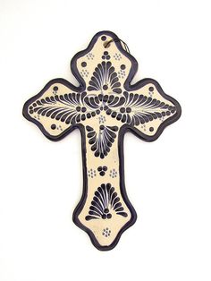 an ornate wooden cross with black and white designs on the front, against a white background