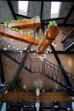 an indoor dining area with wooden tables, black chairs and hanging plants on the wall