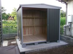 an outdoor storage shed with its doors open and shelves in the back ground next to it