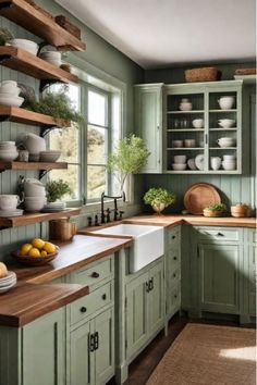 a kitchen filled with lots of green cupboards and white dishes on top of wooden shelves