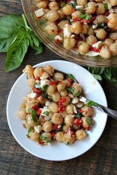 chickpeas and spinach salad in a bowl on a wooden table next to another dish