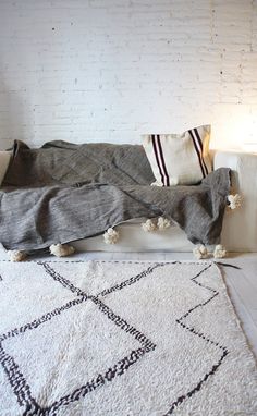 a white rug with pom poms on it in front of a brick wall