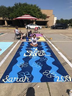 a woman sitting on the ground in front of a large sign that says happy later