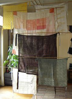 several pieces of cloth hanging on a clothes line in a room with wood flooring