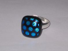 a square ring with blue and green dots on it's sides, sitting on a white surface