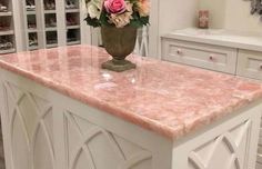 a vase filled with pink and white flowers on top of a marble counter in a kitchen