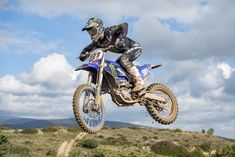 a man riding on the back of a dirt bike in the air over a hill