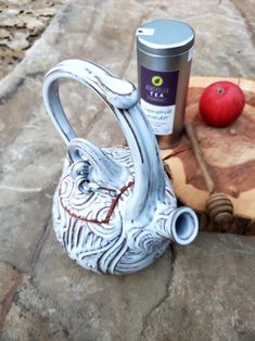 a teapot and cup sitting on top of a stone slab next to an apple