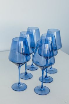 four blue wine glasses sitting on top of a table