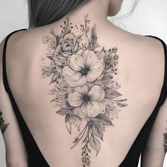 a woman's back tattoo with flowers and leaves