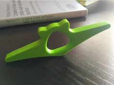 a pair of green scissors sitting on top of a wooden table next to a book