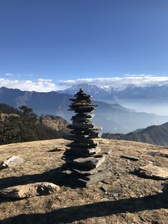 stacked rocks on top of a mountain with mountains in the background