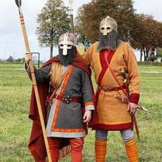 two people dressed in medieval costumes standing next to each other with spears and shields on their heads