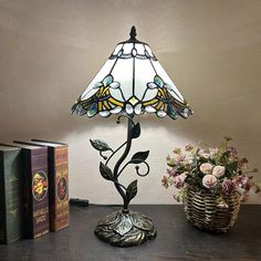 a lamp that is on top of a table next to some books and a basket