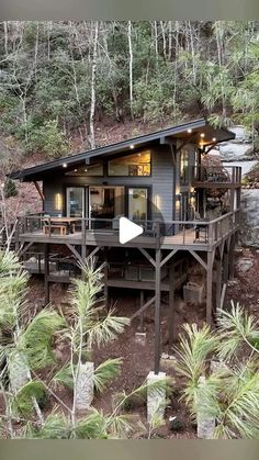 a house on the side of a hill with trees around it and a deck in front