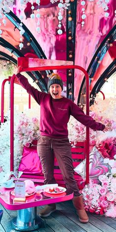 a woman standing on top of a pink bench next to lots of flowers and decorations