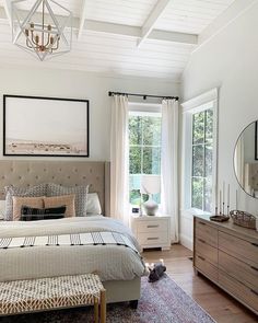 a bedroom with a bed, dresser and mirror in the corner next to a window