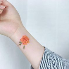 an orange flower tattoo on the wrist