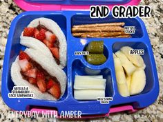 a lunch box with fruit, crackers and pickles in it that is labeled 2nd grader