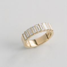 a yellow gold ring with baguetts of diamonds on the side, set against a plain white background