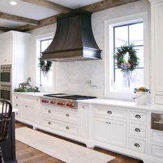 a kitchen with white cabinets and an oven in the center, surrounded by wreaths