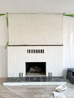 the fireplace is being painted white and has green tape around it's edges,