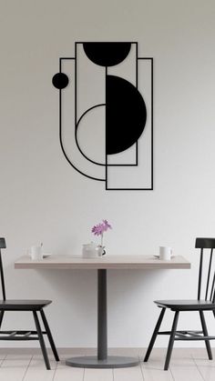 two chairs and a table in front of a wall with an art piece on it