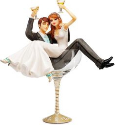 a bride and groom figurine sitting on top of a champagne goblet