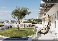 a balcony with a hammock hanging from it's side and grass in the foreground