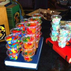 many plastic cups filled with candy on top of a table next to a red book