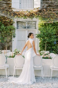 a woman standing in front of a table with white chairs and tables set up for an event