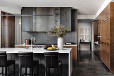 a kitchen with black chairs and white counter tops next to a large center island in the middle of the room