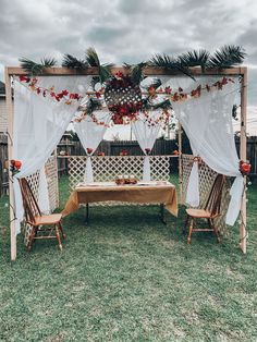 an outdoor wedding set up with white drapes and red flowers on the top table