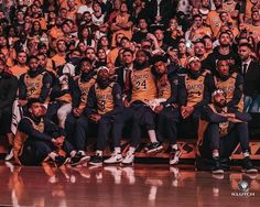 a group of men sitting on top of a basketball court