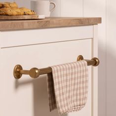 a kitchen towel rack with two towels hanging on it's side and cookies in the background