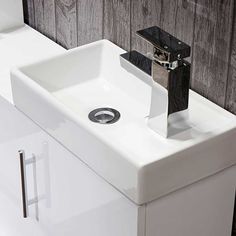 a white bathroom sink sitting under a faucet next to a wall mounted toilet