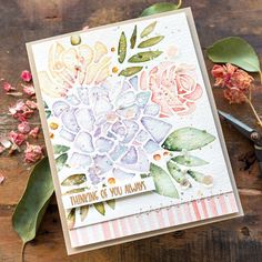 a close up of a card with flowers and scissors on a wooden table next to it