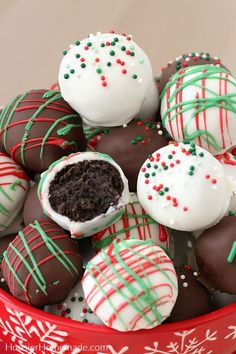 a red bowl filled with white and green chocolate covered truffles on top of a table