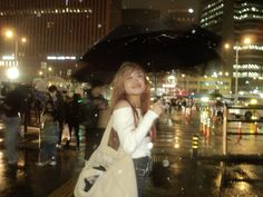 a woman standing in the rain holding an umbrella