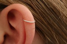 a woman's ear is shown with a thin silver ring on top of it