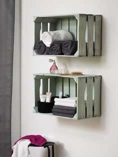 two wooden crates with towels and candles on them are hung on the wall in a bathroom