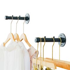 three wooden clothes hangers and two metal hooks on the same rod, one holding white shirts