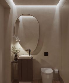 a white toilet sitting next to a bathroom sink under a round mirror on the wall